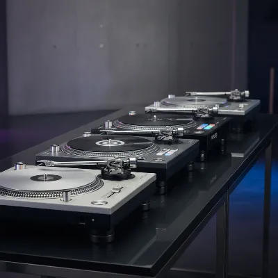 A side-by-side visual comparison of five different direct drive DJ turntables, showcasing their varied designs and features, arranged neatly on a sleek table in a modern setting.