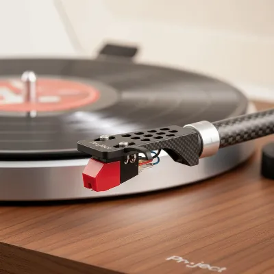 Close-up shot of the Pro-Ject Debut Carbon EVO turntable's carbon fiber tonearm and Ortofon 2M Red cartridge