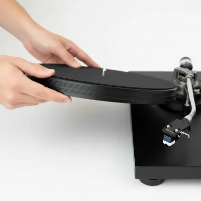 Removing the platter from a belt-drive record player to access the old belt.
