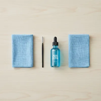 A collection of record player maintenance tools, including a stylus brush, record cleaning fluid, and microfiber cloths.